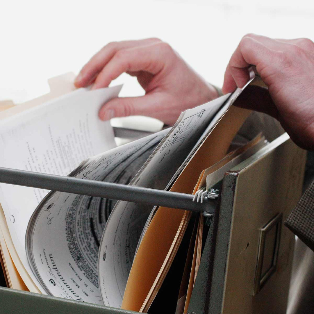 Picture of a person's hands going through a file in a filing cabinet